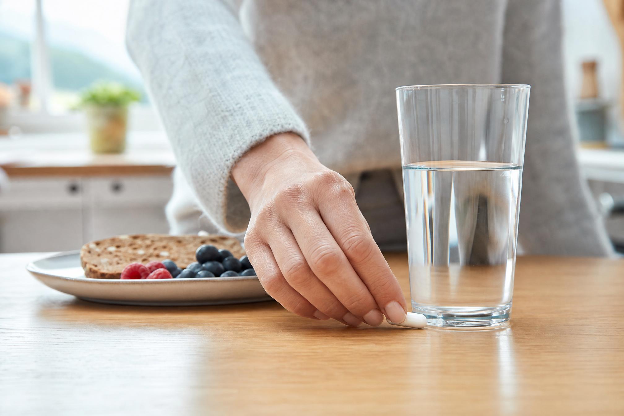 Une capsule Tyrexin avec un verre d'eau et un petit-déjeuner sain
